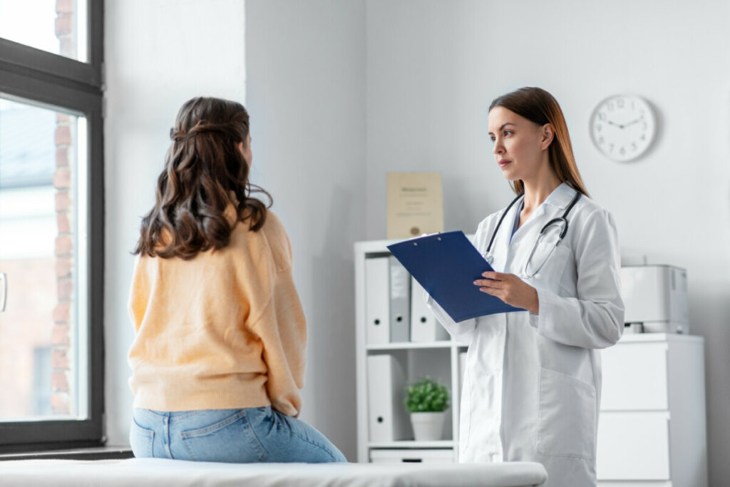 doctor with clipboard and woman at hospital